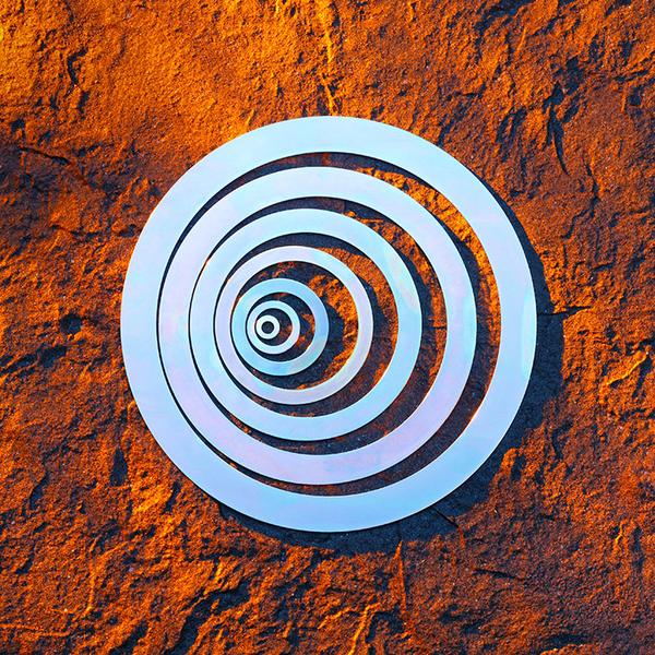 Unterlegscheiben in verschiedenen Größen, das auf einer strukturierten, orangefarbenen Oberfläche platziert ist. Die Ringe sind in einem hellen, glänzenden Material gehalten, das Licht reflektiert.