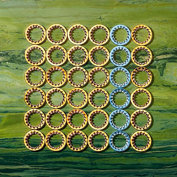 Eine Sammlung von runden, goldenen und blauen Ringen auf einem strukturierten grünen Hintergrund. Die Ringe sind in einer ordentlichen 7x7-Anordnung angeordnet, wobei die goldenen Ringe in der Mehrheit sind und die blauen Ringe in der Mitte hervorgehoben werden.