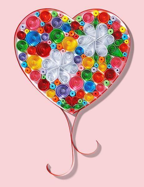 Ein herzförmiges Kunstwerk aus bunten Papierstreifen in unterschiedlichen Farben, verziert mit zwei weißen, blütenähnlichen Formen. Der Hintergrund ist rosa. Das Herz hat einen eleganten, geschwungenen Schwung am unteren Ende.
