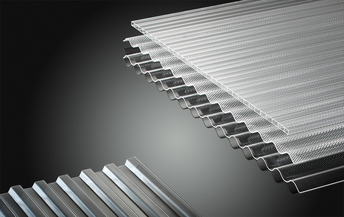 Eine Anordnung von transparenten, geriffelten Plexiglasplatten, die übereinander gestapelt sind. Die Platten unterscheiden sich in Struktur und Breite, wobei einige glatt und andere mit einem speziellen Muster versehen sind. Der Hintergrund ist dunkel.