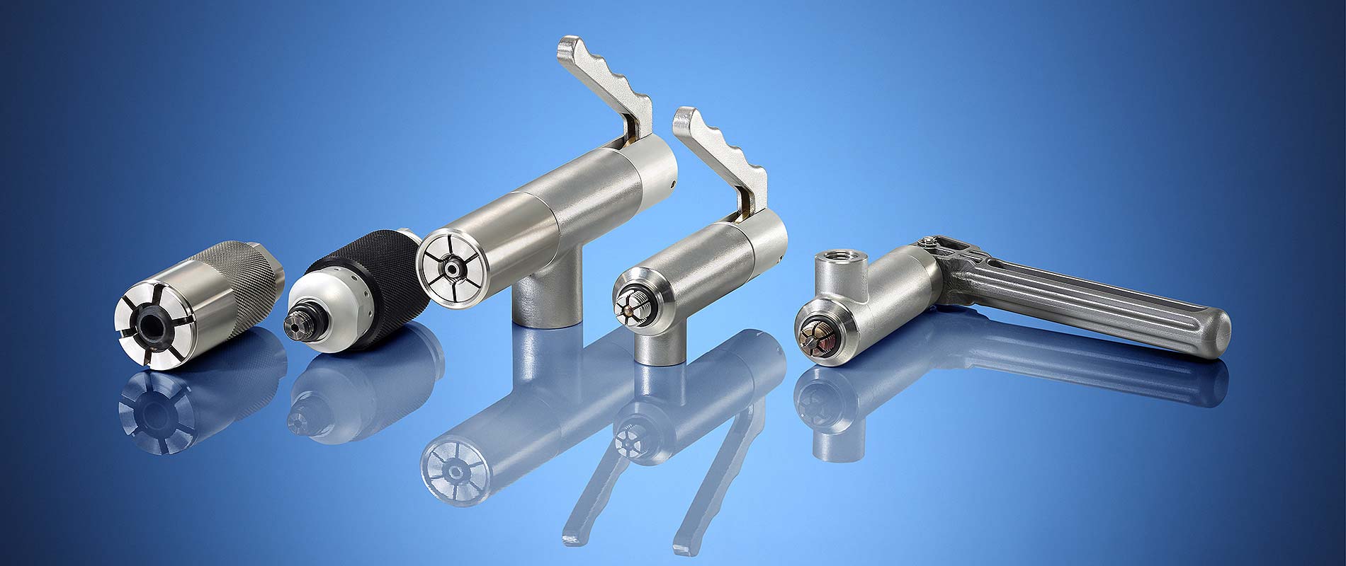 Fünf verschiedene Werkzeuge aus Metall auf einem blauen Hintergrund. Die Werkzeuge haben unterschiedliche Formen und Größen, die eine Verbindung zu präzisen mechanischen Anwendungen suggerieren.
